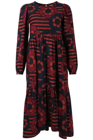 Danefæ Kjole Danoktober  Cord Power Flower Kjolen er en iøjnefaldende og kunstnerisk designet midi kjole med et markant mønster. i en mørkeblå bundfarve med store blomster  og røde striber i baggrunden. Modellen er en løs og komfortabel pasform med et let empire snit (indsnit under brystet) som falder i let rynket lag ned mod kanten. Danefæ Kjole Danoktober cord Power Flower er en midi model der har lange ærmer med puf. Rund halsudskæring med en dråbeåbning og lille knap i nakken Udtrykket er boheme og retro-inspireret, og mønsteret giver kjolen et varmt og livligt look. Den kan styles både afslappet med støvler og cardigan eller mere festligt med smykker og hæle. Et godt og sikker valg i en skøn babyfløjl.